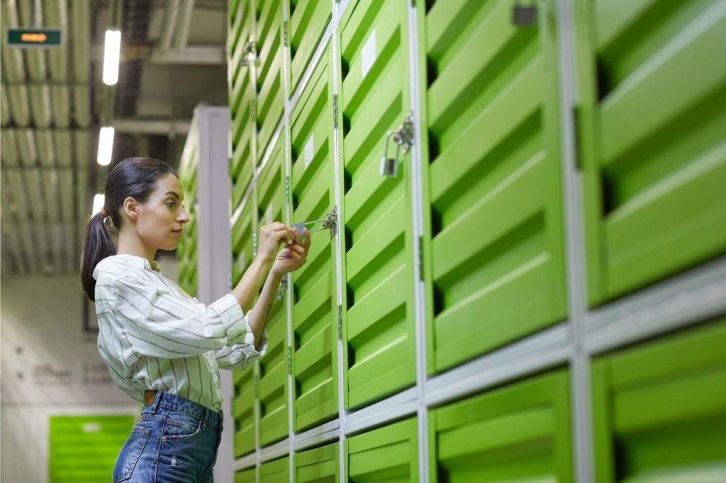 Na foto, uma mulher trancando o seu compartimento de self storage