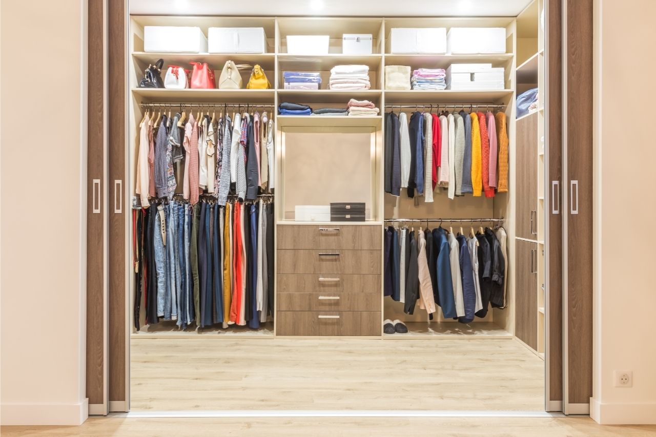 na foto, um armário com roupas e caixas organizadas