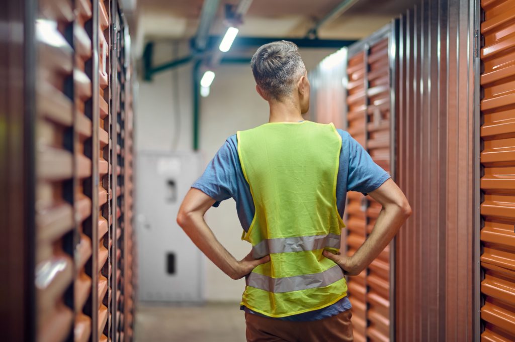Homem de costas dentro de um self storage observando os compartimentos