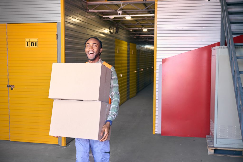 Homem contente carregando caixa de papelão e posando para câmera