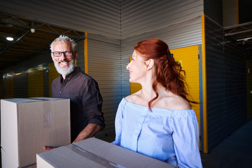 Casal se olhando e segurando caixas de papelão com itens para guardar no self storage