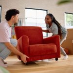 Casal feliz carregando móveis para sua nova casa.