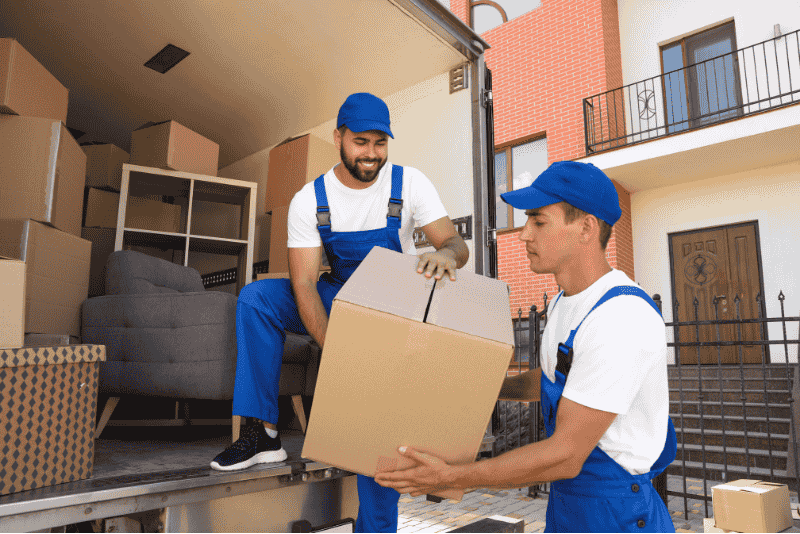 Homens sorridentes colocando caixas de mudança em um caminhão