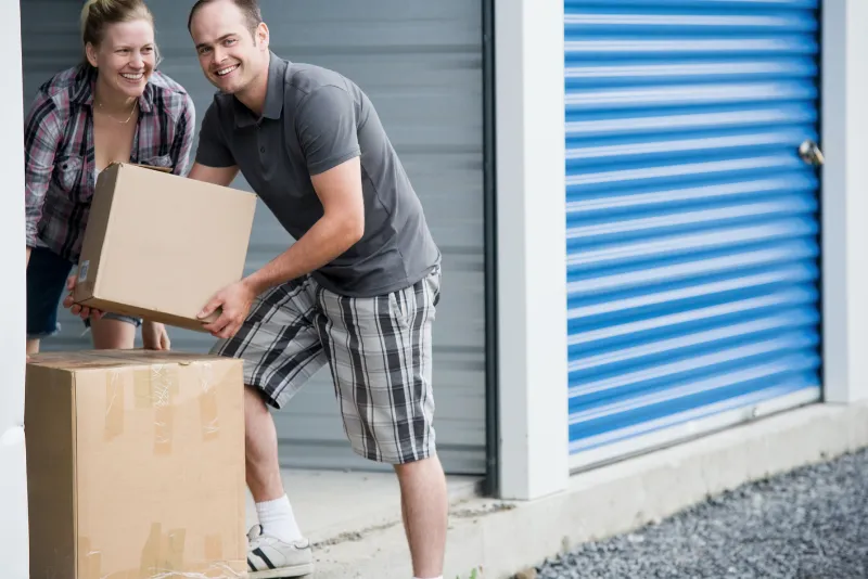 Casal sorridente colocando caixas em um box de self storage