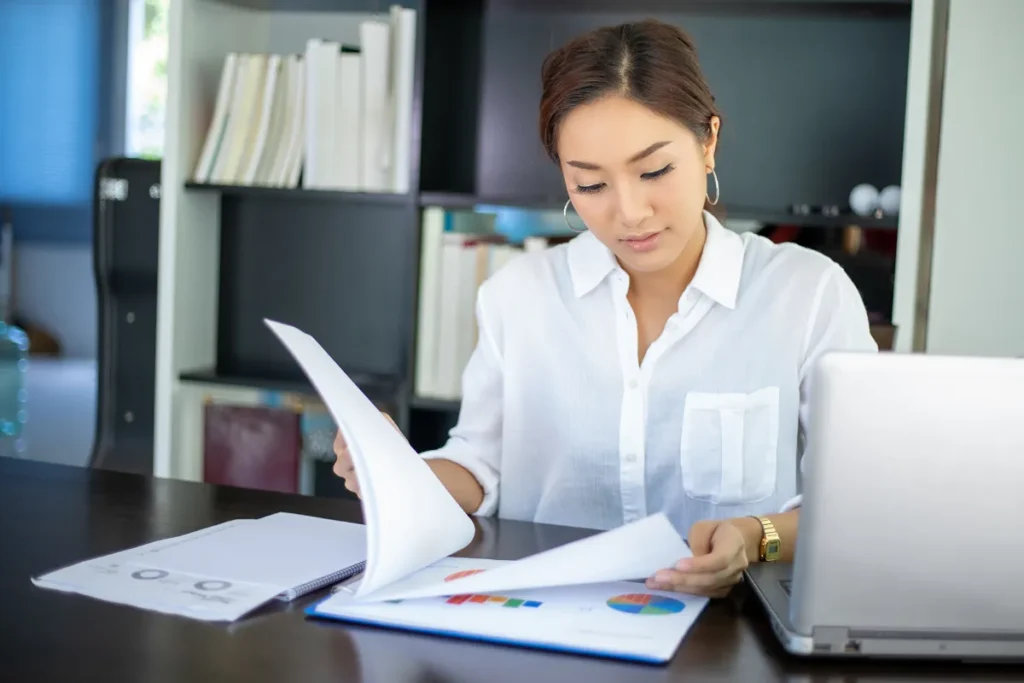 Mulher sentada sobre a mesa analisando inventário de bens armazenados