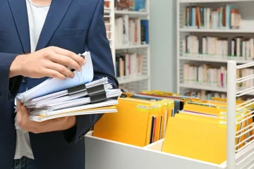Pessoa segurando pasta com vários documentos